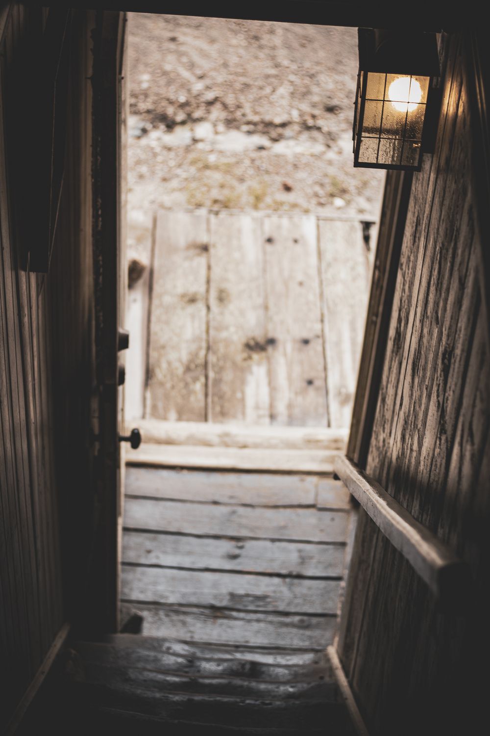 Silhouettes of window frames in a dark wooden structure casting dramatic shadows against rustic wooden walls.