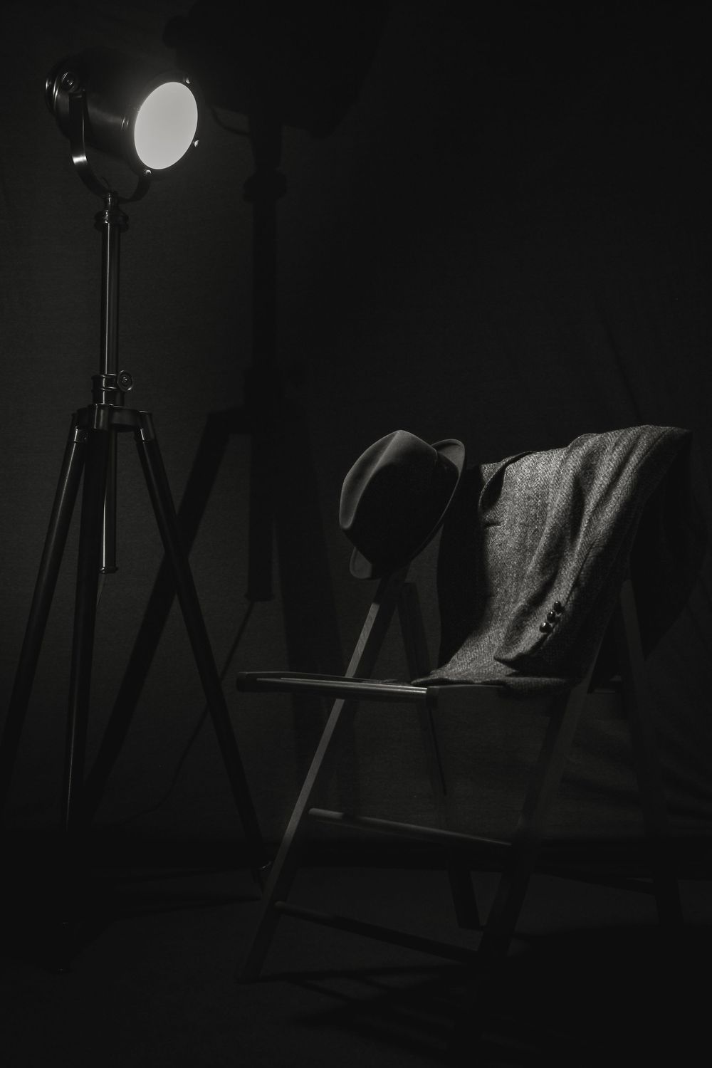 A dark and moody studio setup with lighting equipment and reflectors silhouetted against a black background.