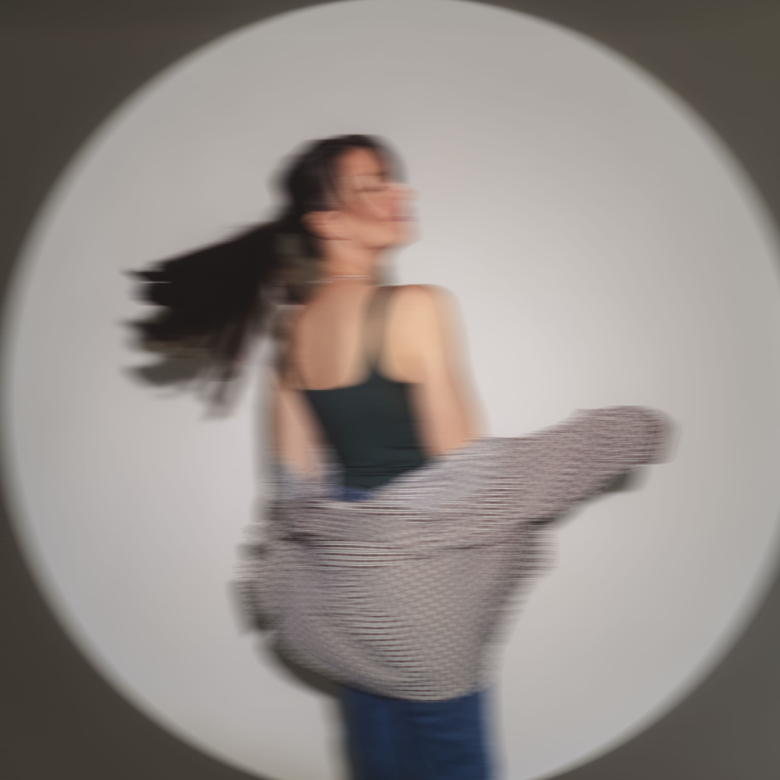 Dynamic motion blur portrait with oval spotlight effect in studio setting.