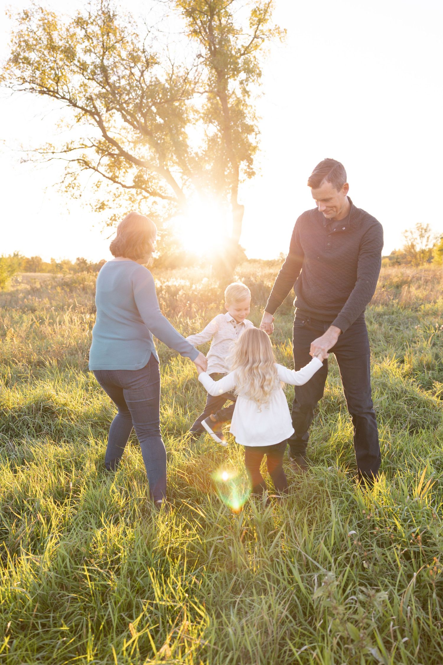 Family playing together in a sunlit field at sunset.