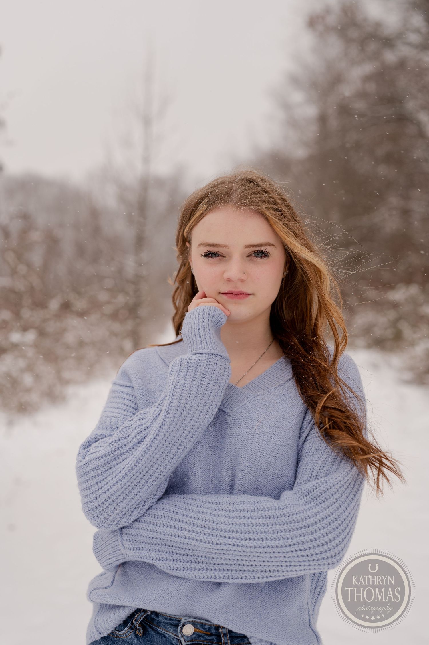 Close-up winter portrait of person in blue sweater with long hair.