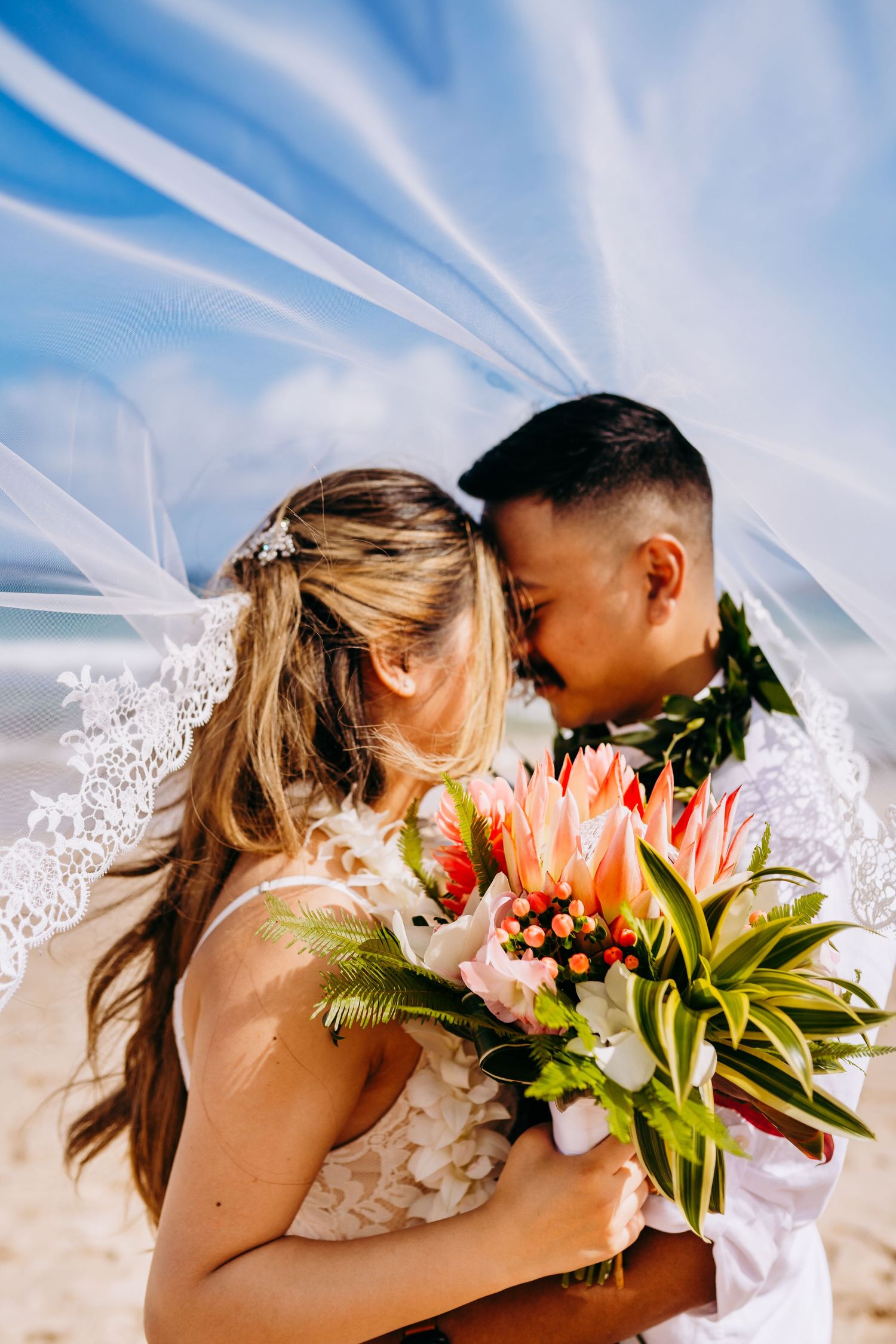 Tropical beach wedding portraits with colorful floral bouquet and flowing veil. Maui Hawaii wailea kihei makena beach wedding ceremony