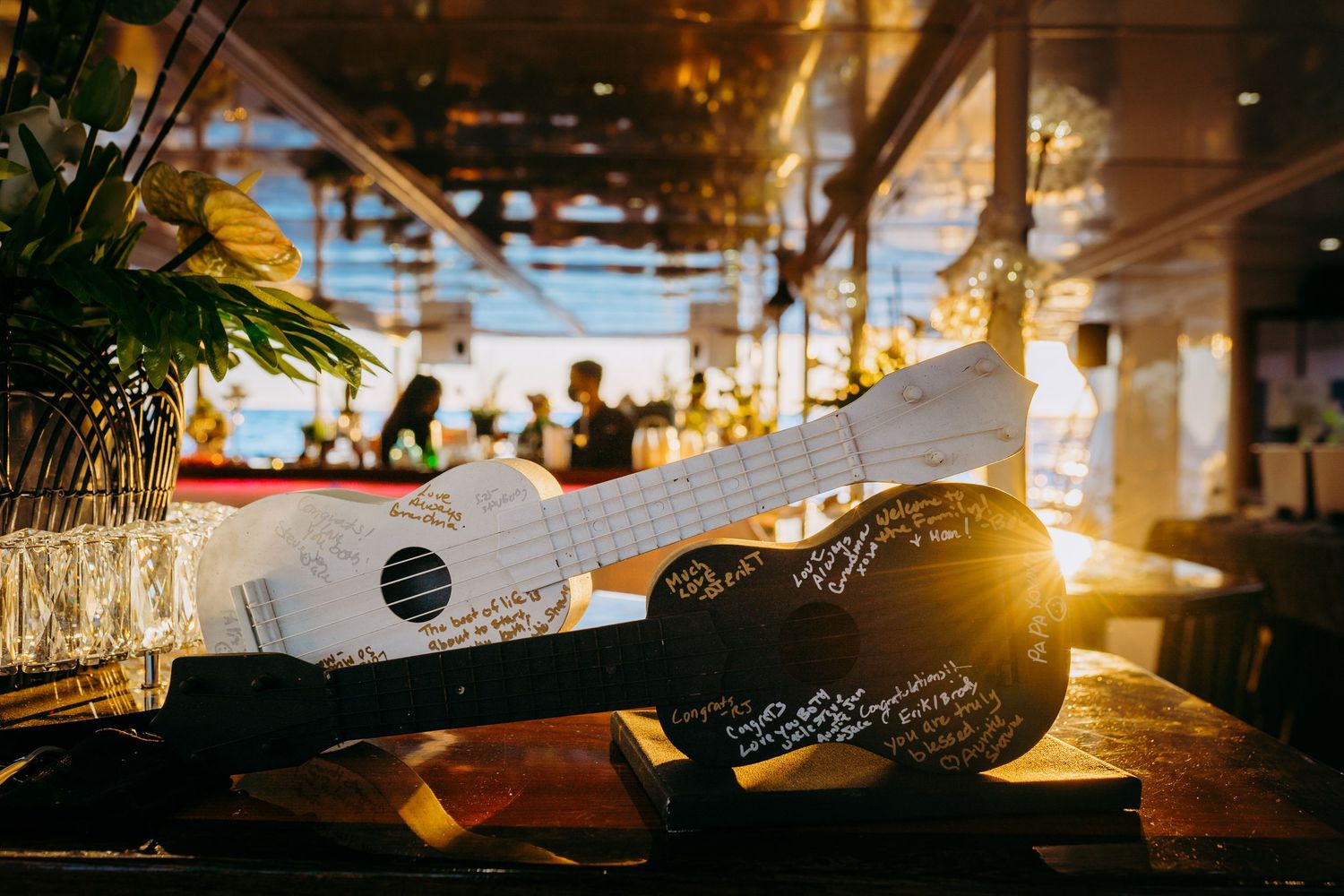 Wedding reception detail of decorative ukulele on illuminated table at sunset for trilogy hawaii wedding ceremony. Catamaran wedding maui