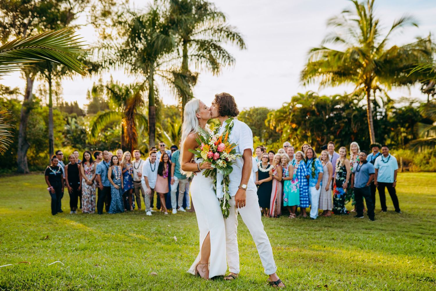 Garden wedding ceremony with guests gathered on a lawn surrounded by tropical palm trees. Maui Hawaii wedding