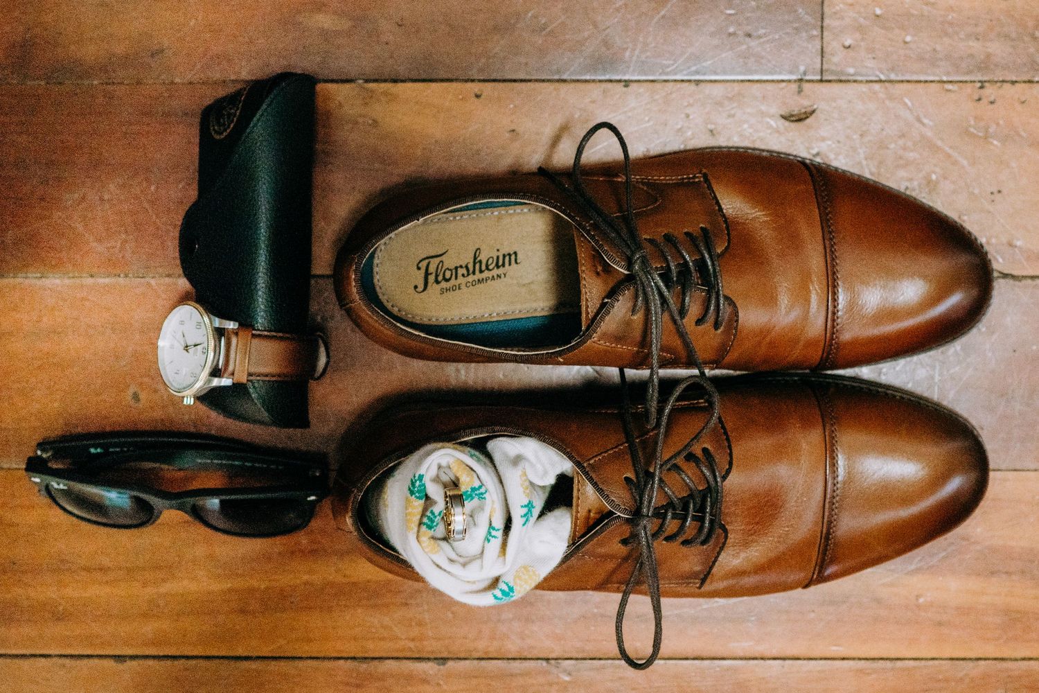 Brown leather dress shoes and wedding rings arranged on wooden floor for detail shot. Maui Hawaii Wailea Kihei Mill House Maui wedding