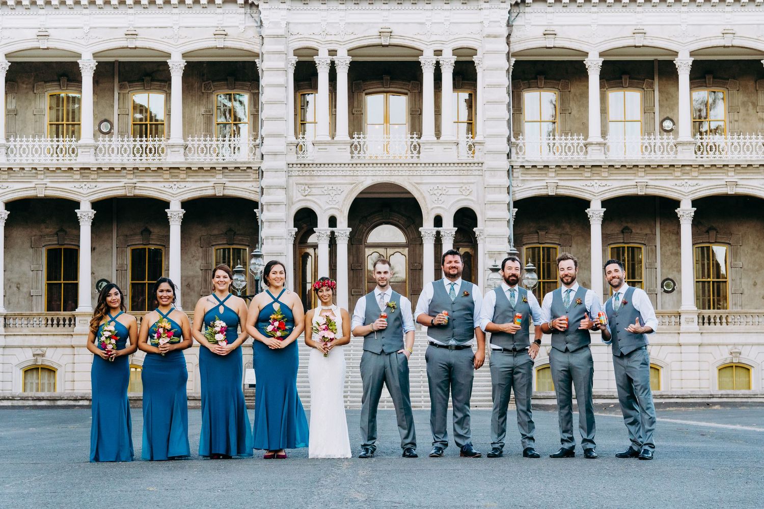 Wedding party in blue and gray attire posed in front of classical architecture.  Maui Hawaii Honolulu Iolani palace wedding
