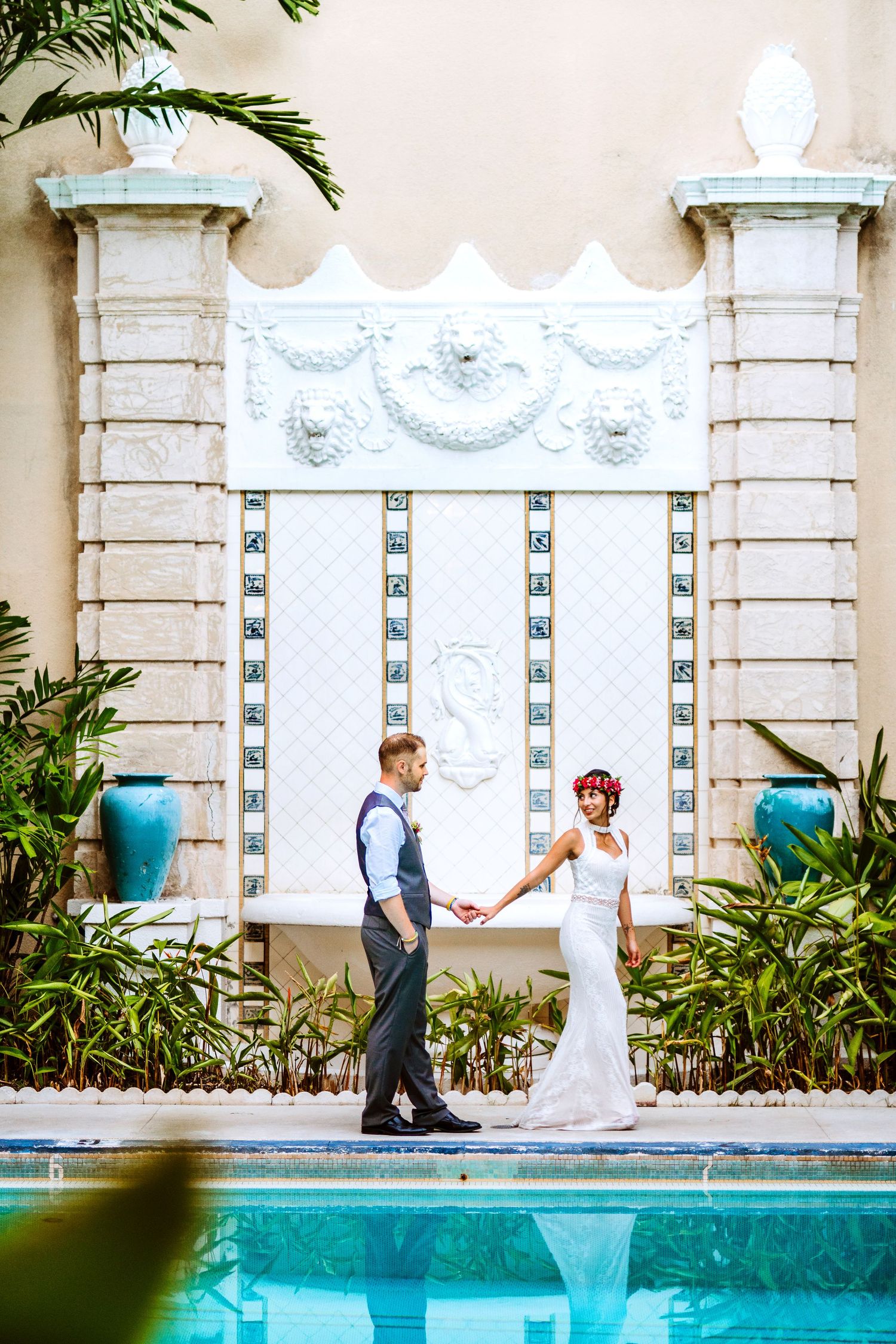 Elegant couple walking along a poolside with ornate white architectural details.  Maui Hawaii Ohau Hawaii Honolulu Cafe Julia Wedding