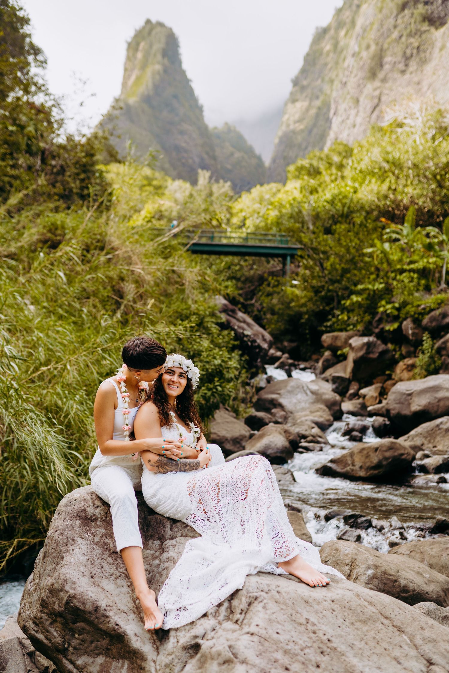 Wedding couple poses on rocky terrain with dramatic mountain peaks in the background. Maui Hawaii iao wailea same sex wedding LGBTQ