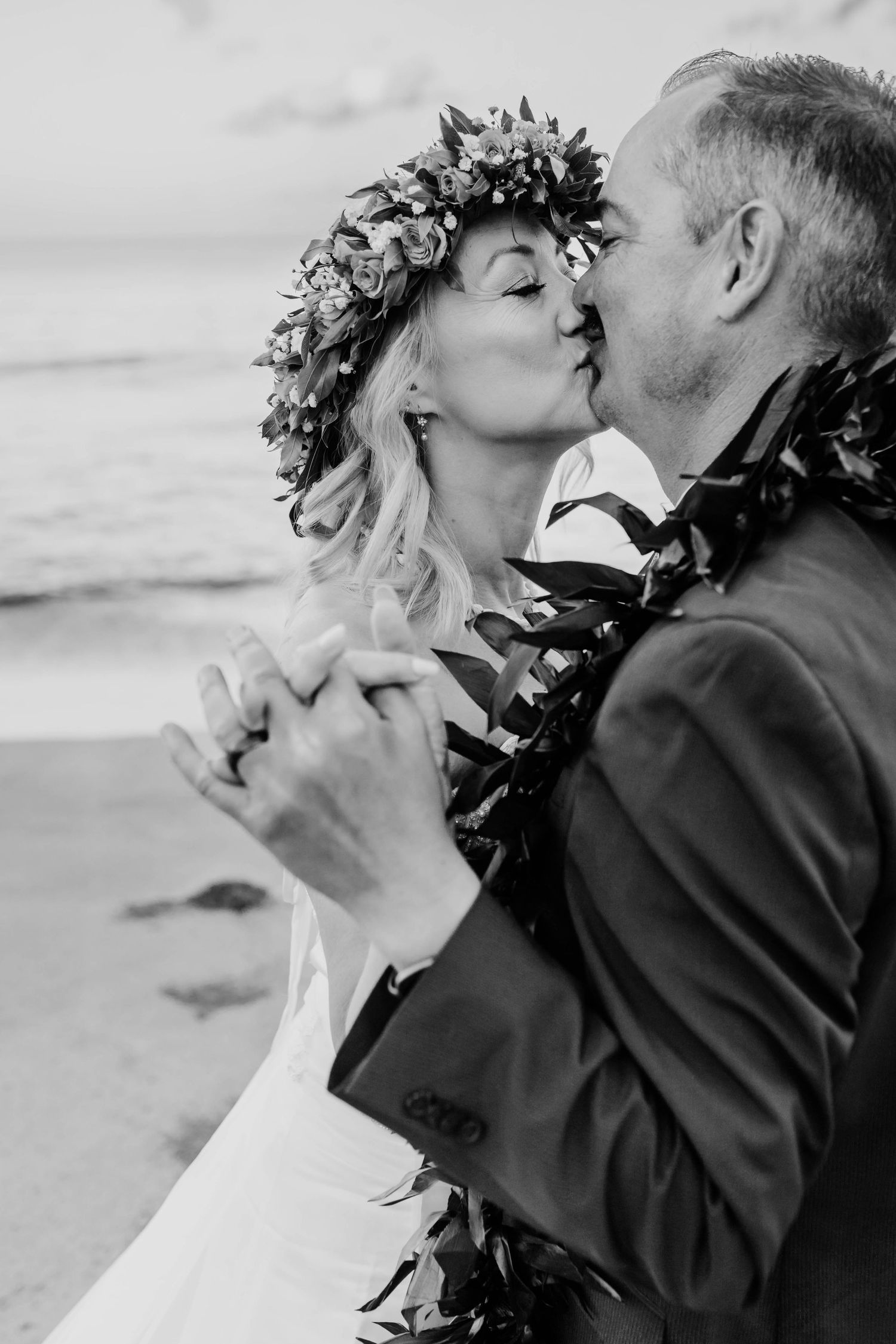 Couple in wedding attire share romantic black and white kiss on beach in Hawaii for beach destination wedding in maui hawaii.