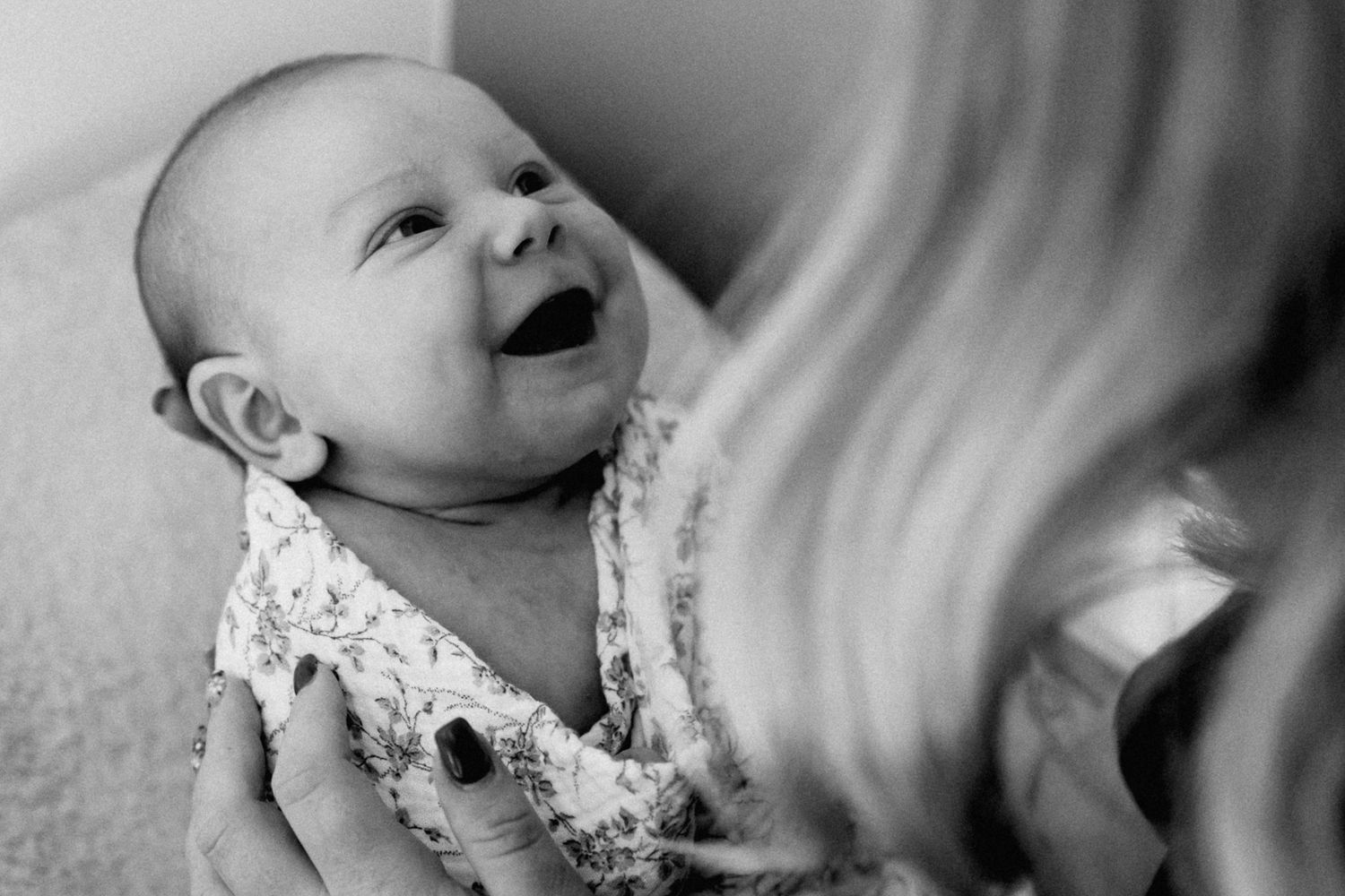 capturer le sourire d'un bebe en interaction avec sa maman pendant une seance photo de naissance a domicile a Lille