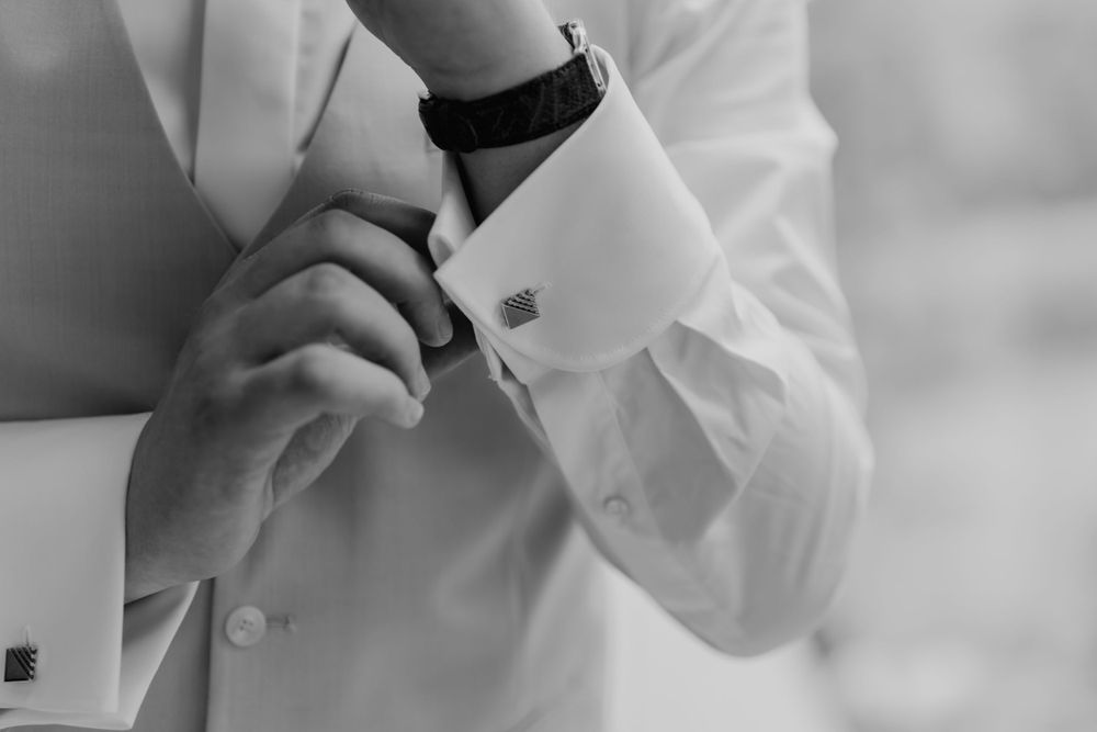 Black and white detail shot of hands adjusting formal white shirt cuffs.