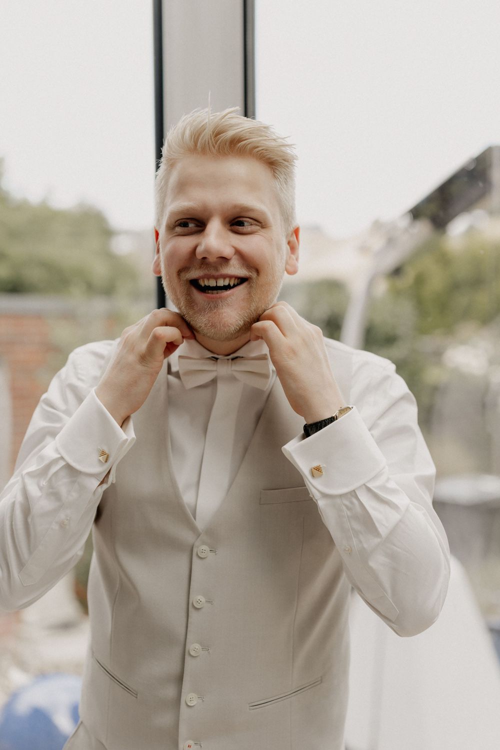 Candid moment of wedding day preparation while adjusting bow tie.