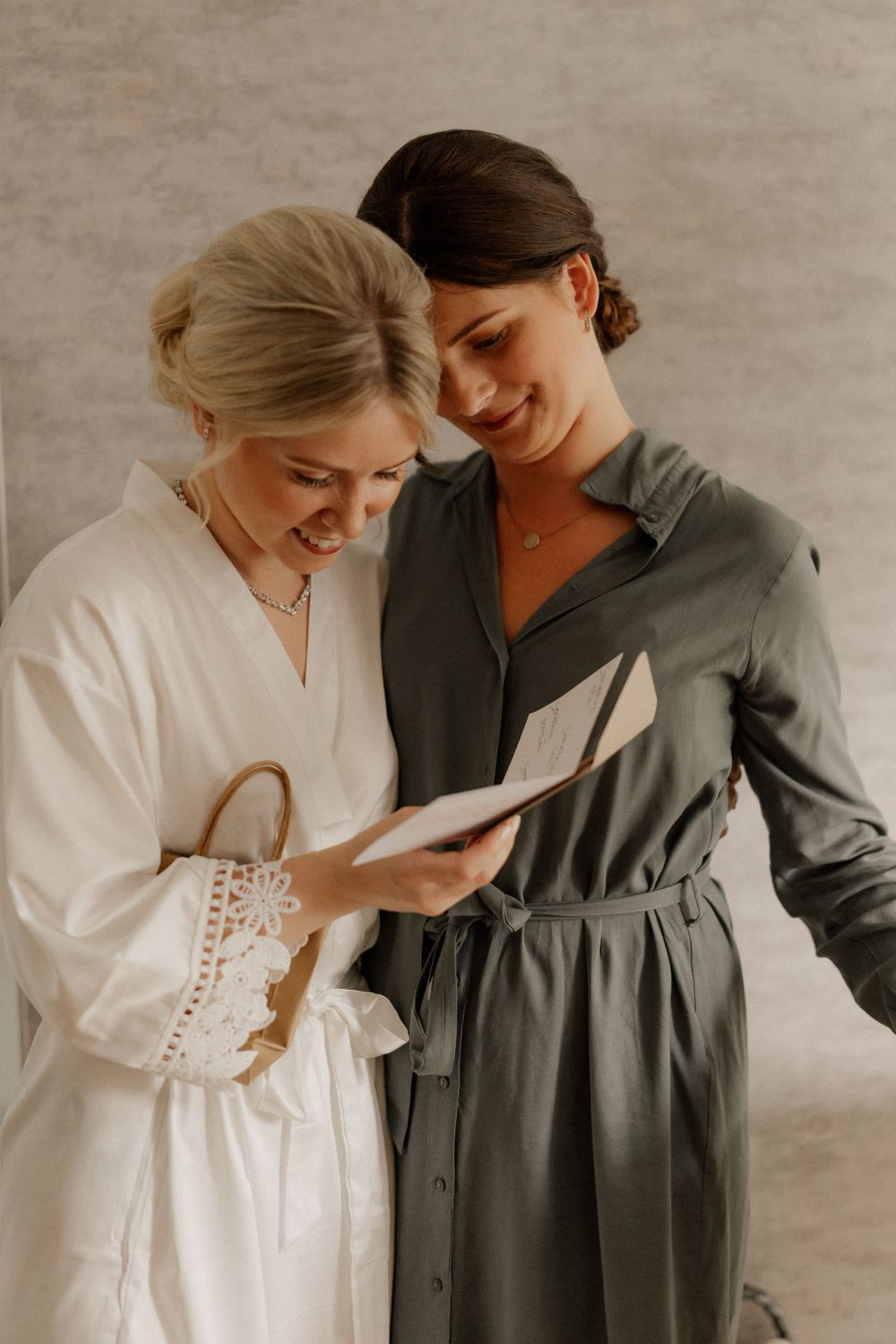 Two people sharing a joyful moment while looking at something on paper in a warm-lit room.