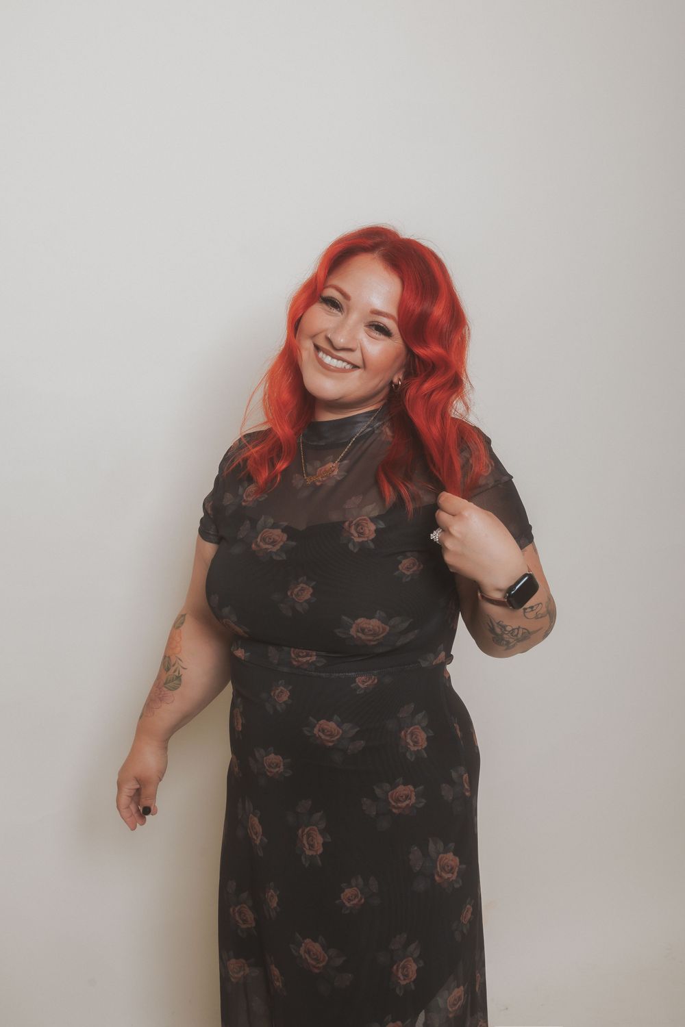 Fashion portrait of woman with vibrant red hair in black floral dress.