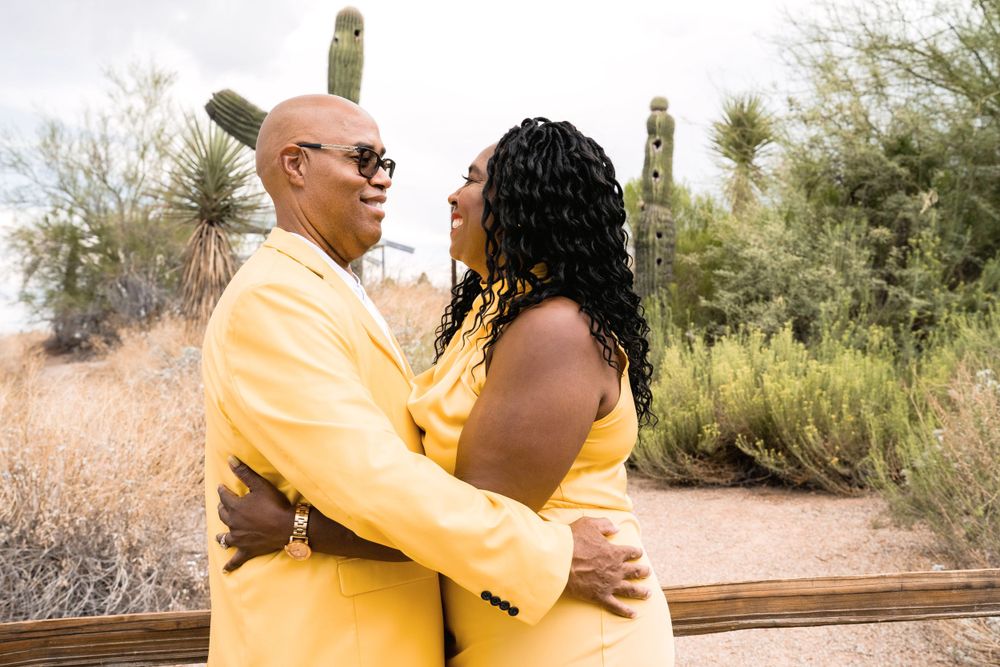 Couple in matching yellow outfits share romantic moment in desert landscape.