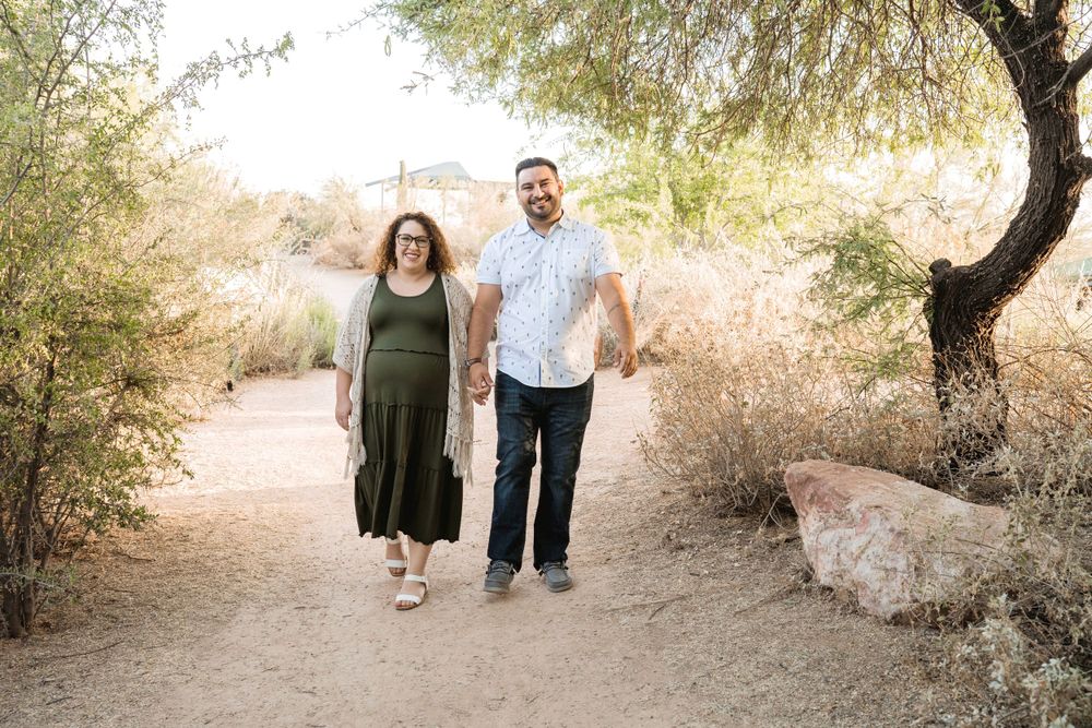 A couple walks together on a desert trail surrounded by natural vegetation.