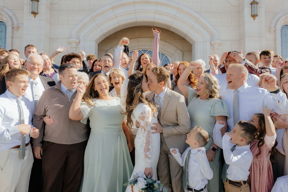 Happy bride and groom surrounded by cheering family and friends at temple wedding.