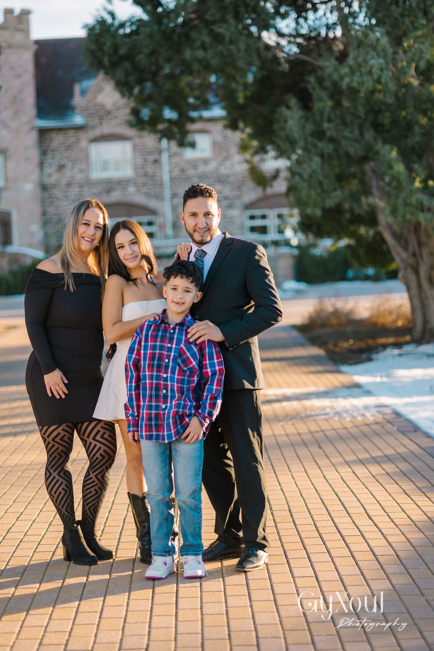 Professional outdoor family portrait with stone building backdrop.