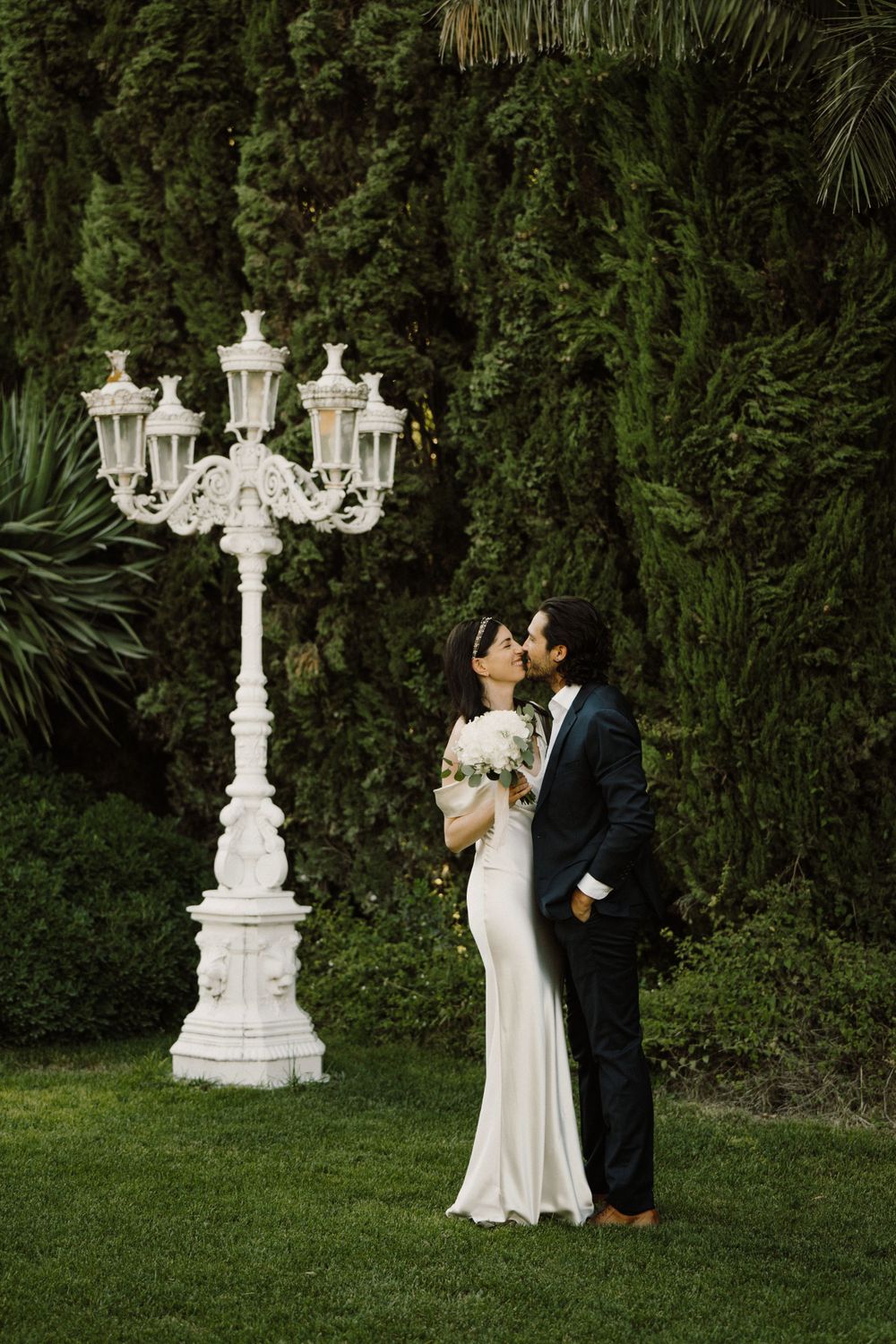 Bride and groom giving a kiss in a Sicilian villa garden.