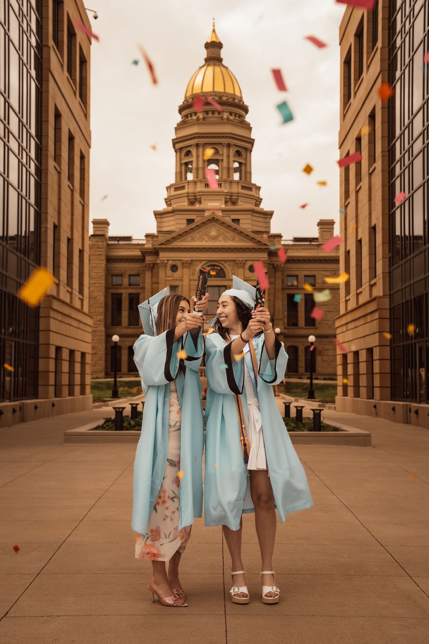 People in red graduation gowns celebrating on stone building walkway with lanterns.