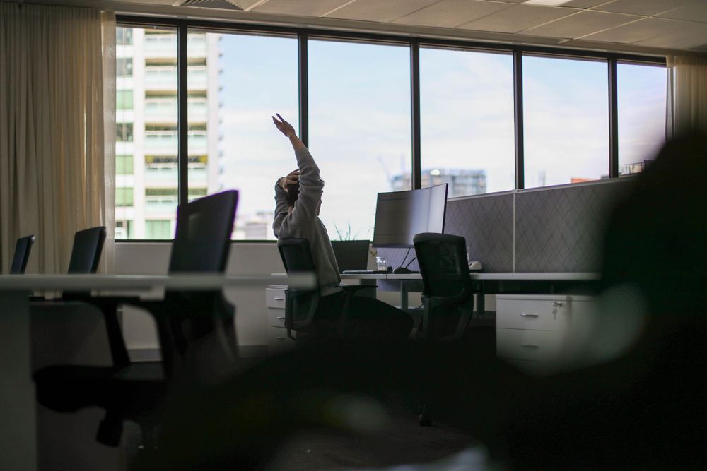 Office workspace silhouette against large windows with city backdrop.