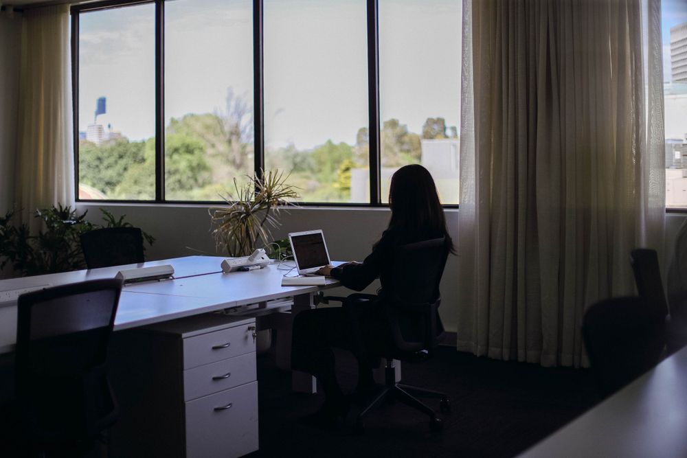 Quiet office workspace with desktop computer setup next to large windows with natural light.