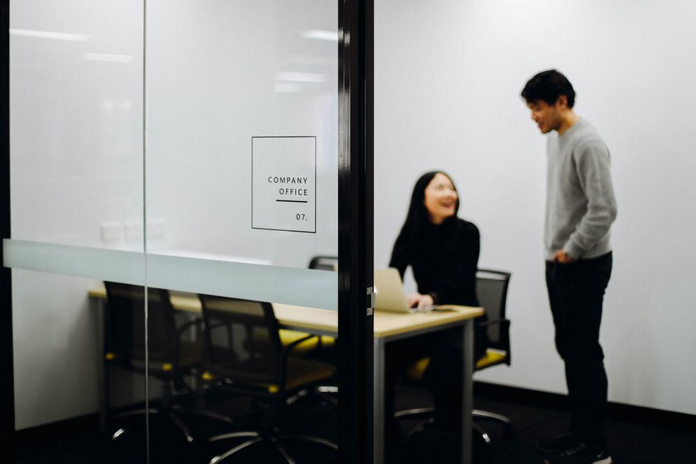 Two people having a discussion in a modern office meeting room.