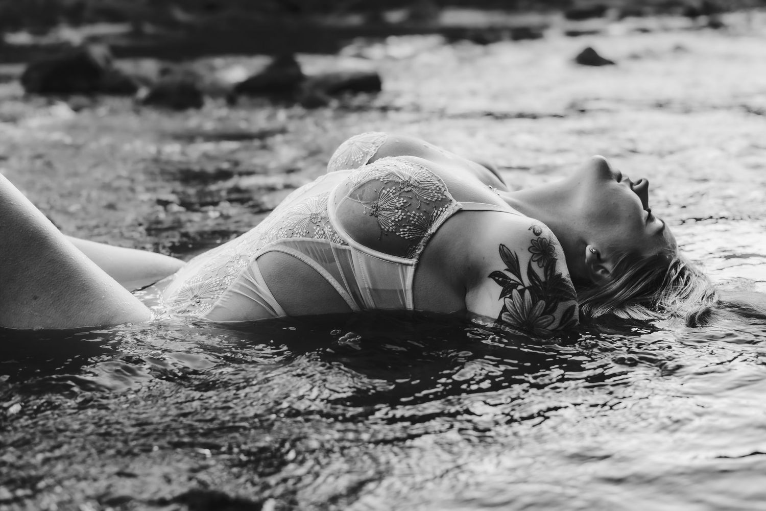 Artistic black and white portrait of person lying in shallow water.