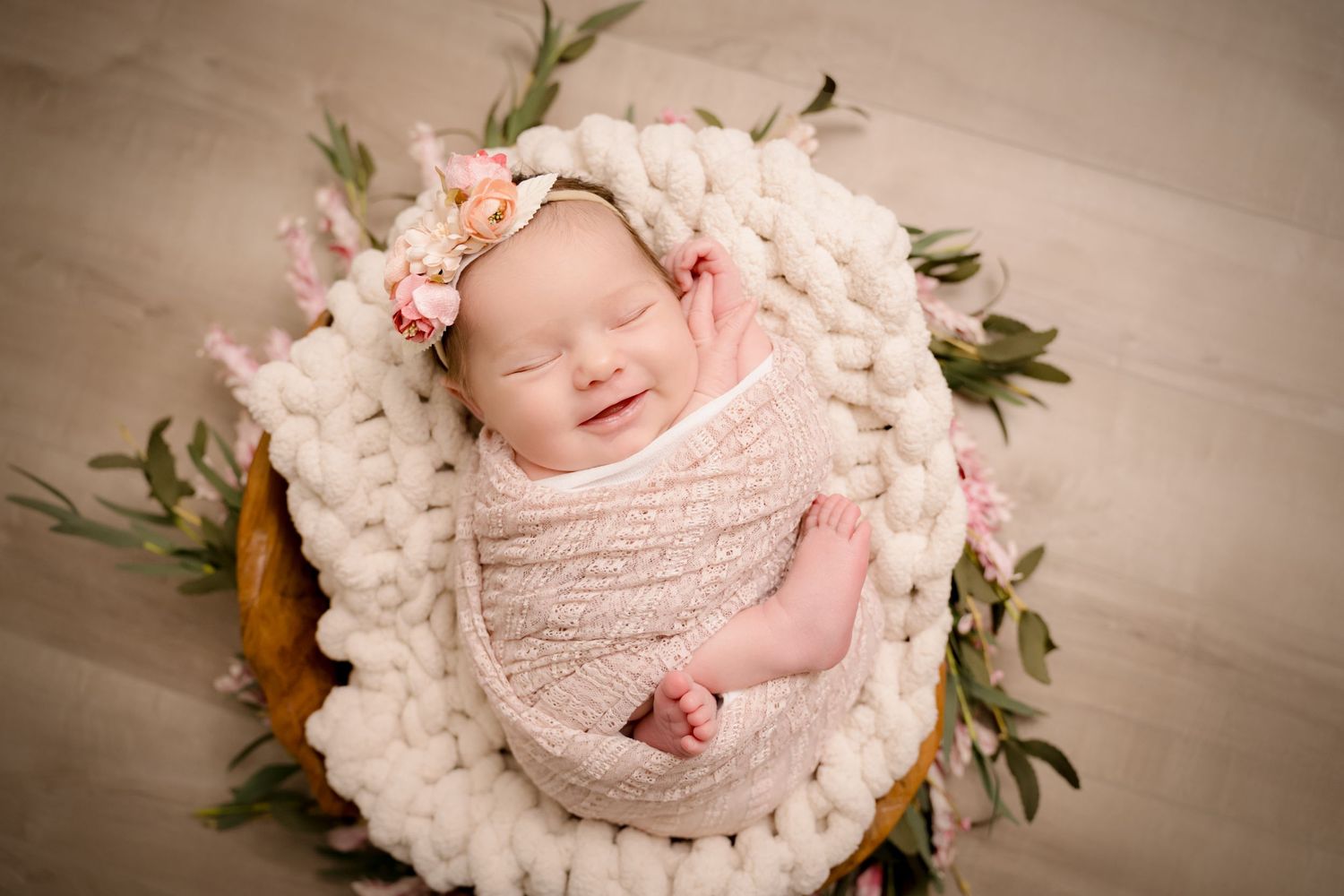 Newborn photoshoot Saskatoon and Warman, baby girl in dusty pink and floral props with gold posing flowers prop wrapped, smiling baby