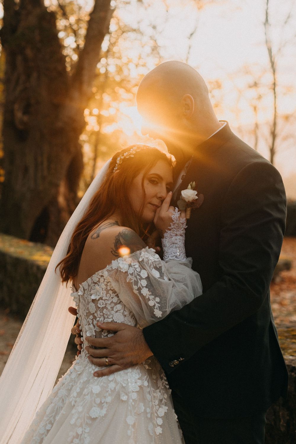 A romantic sunset wedding photoshoot in a forest with golden light streaming through autumn trees.