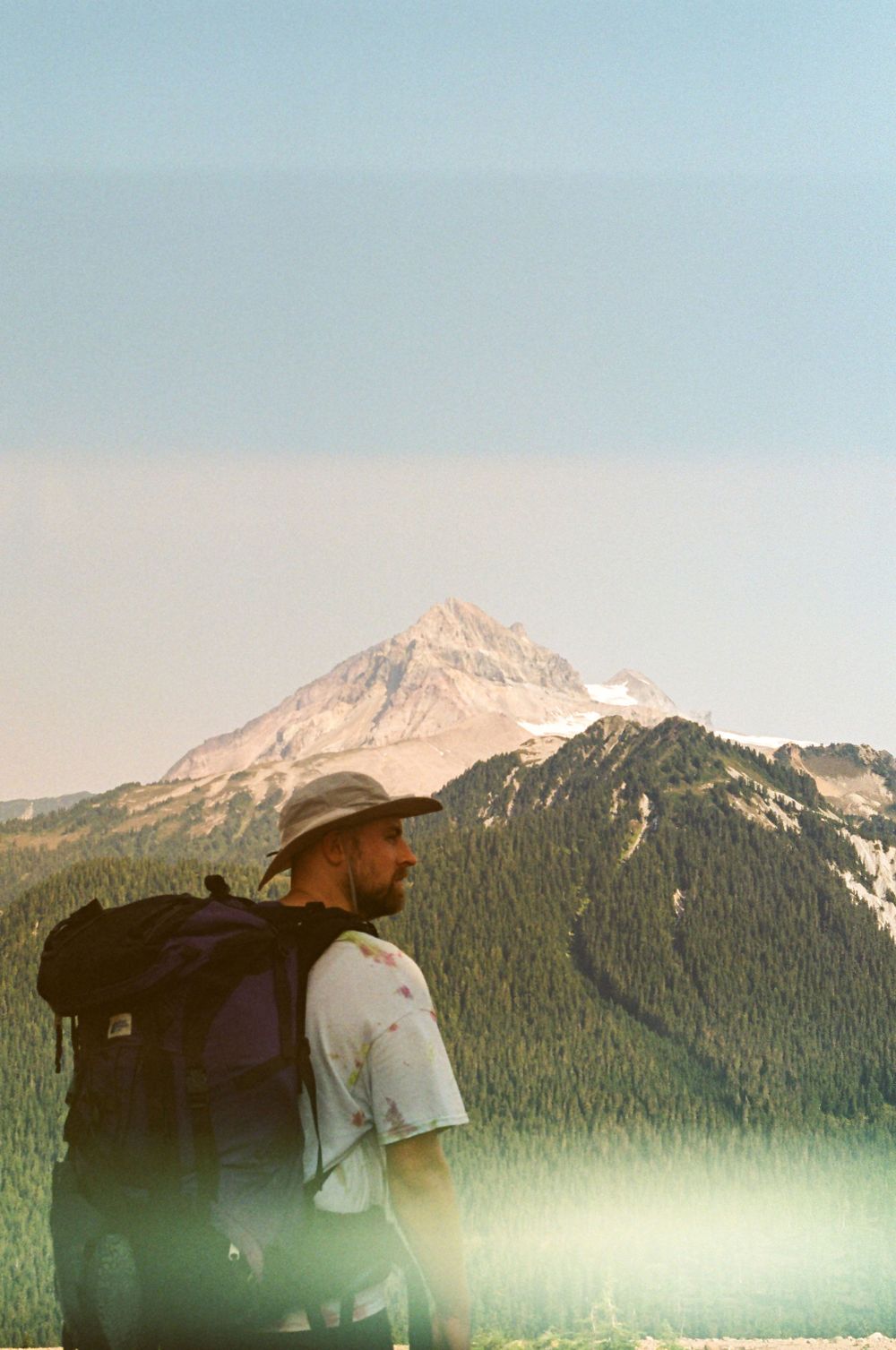 Backpackers trek along a high-altitude trail with dramatic mountain vistas in the background.