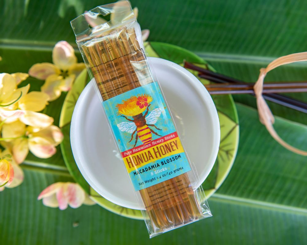 Honey Flower brand brown candy package displayed on white plate with tropical leaves.