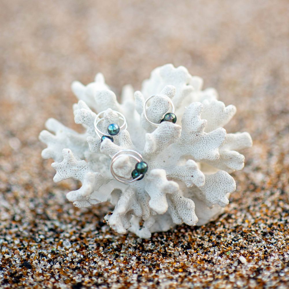 White coral jewelry piece with blue crystals on sandy beach background.