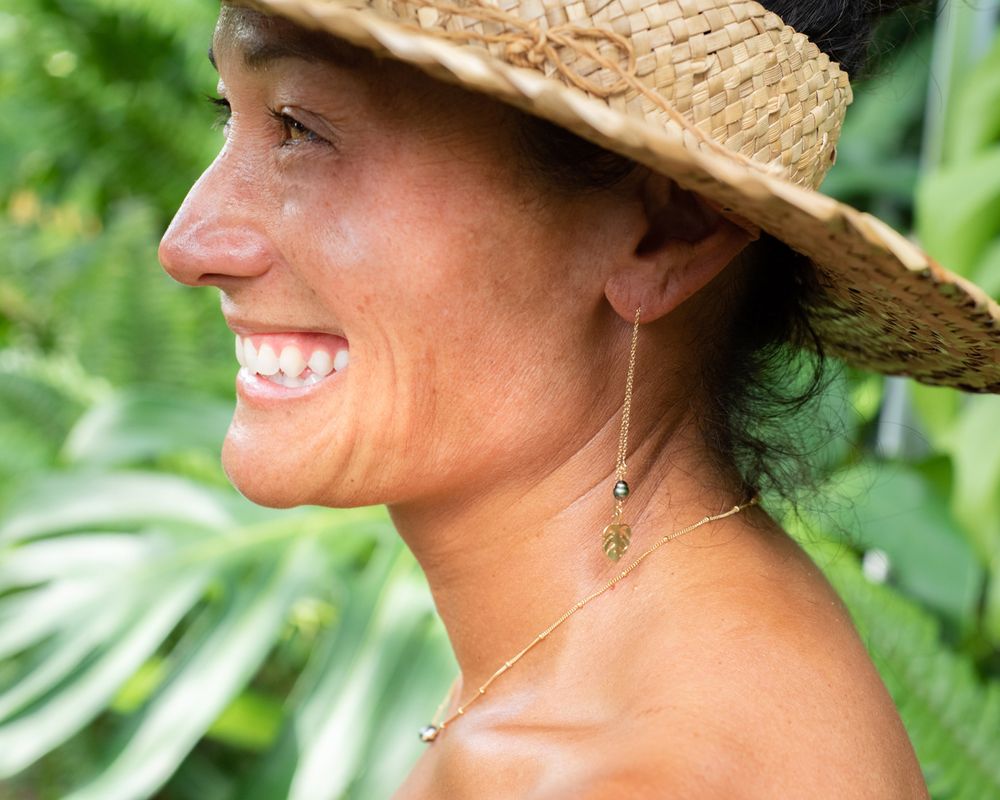 Elegant nature-inspired jewelry displayed outdoors with tropical greenery backdrop.