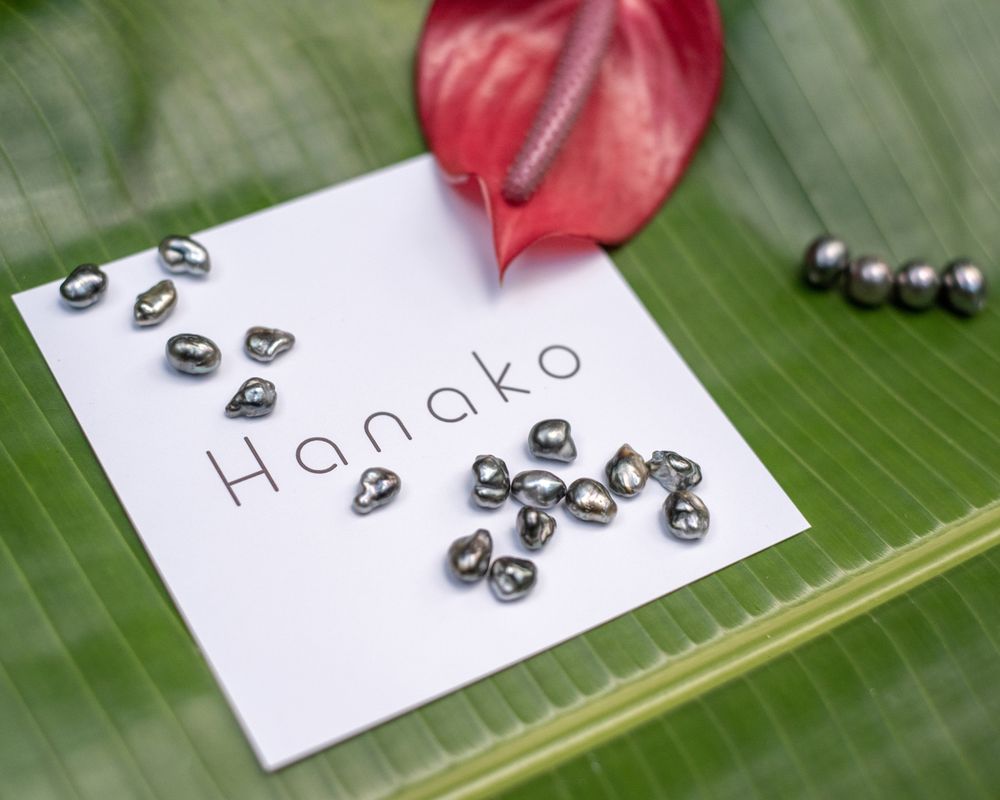 Silver beads and jewelry components arranged on Hanako branded card with red anthurium leaf.