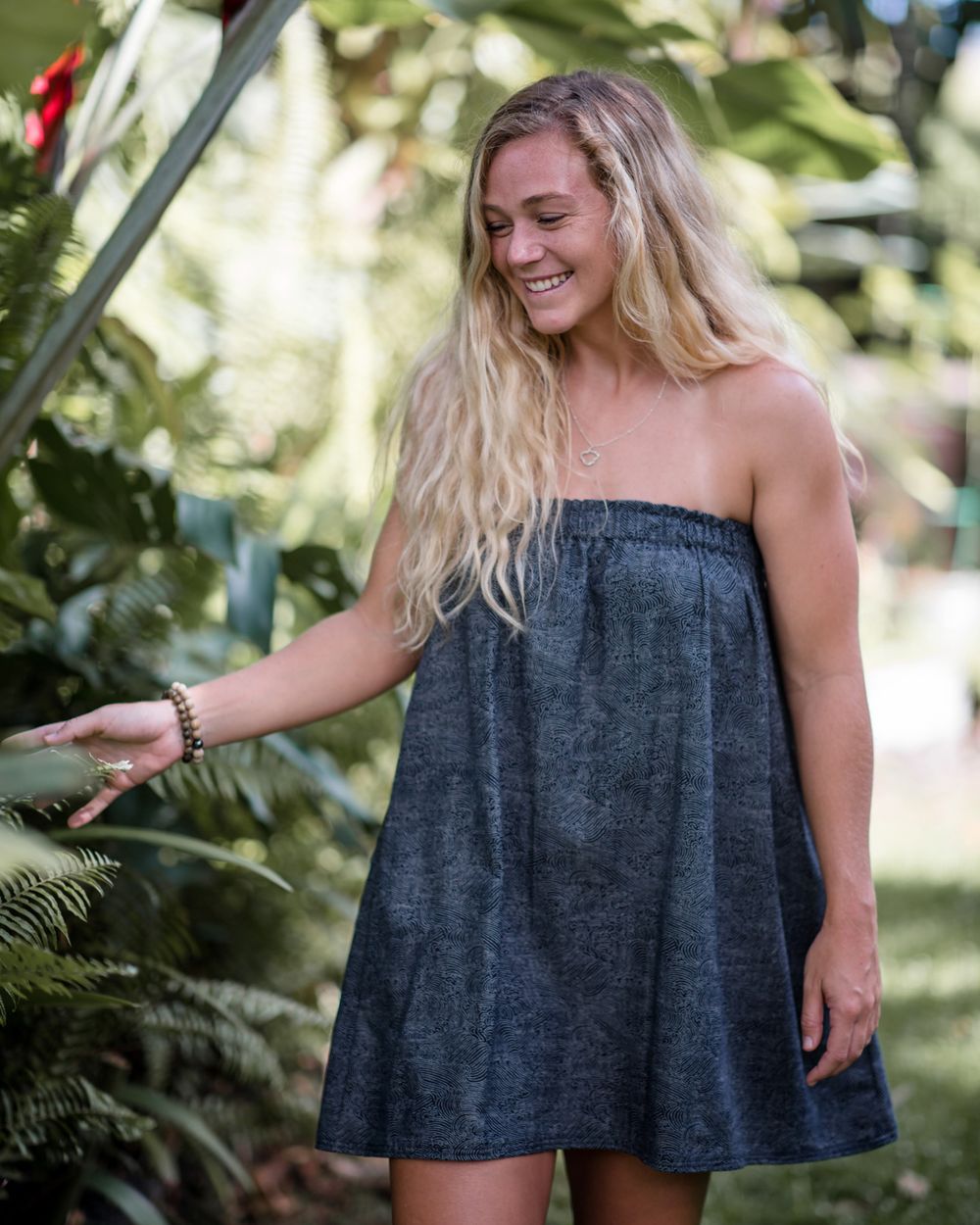 Woman in casual denim dress enjoying a tropical garden setting.