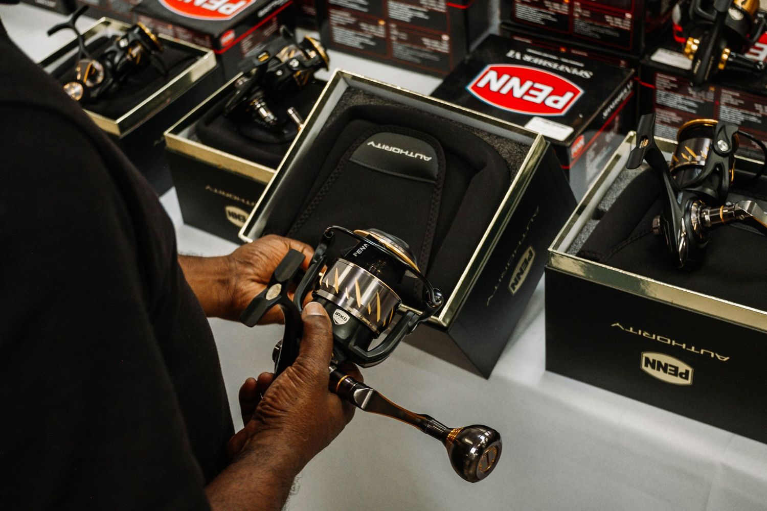 Close up of hands inspecting high-end fishing reel at retail display.