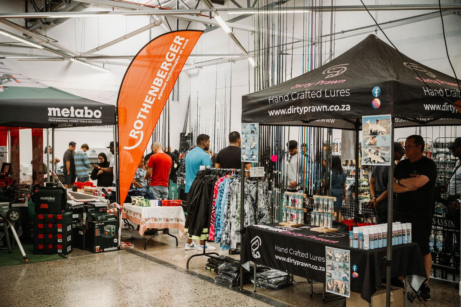 Fishing equipment vendor booths with orange Metabo banner at indoor trade show.