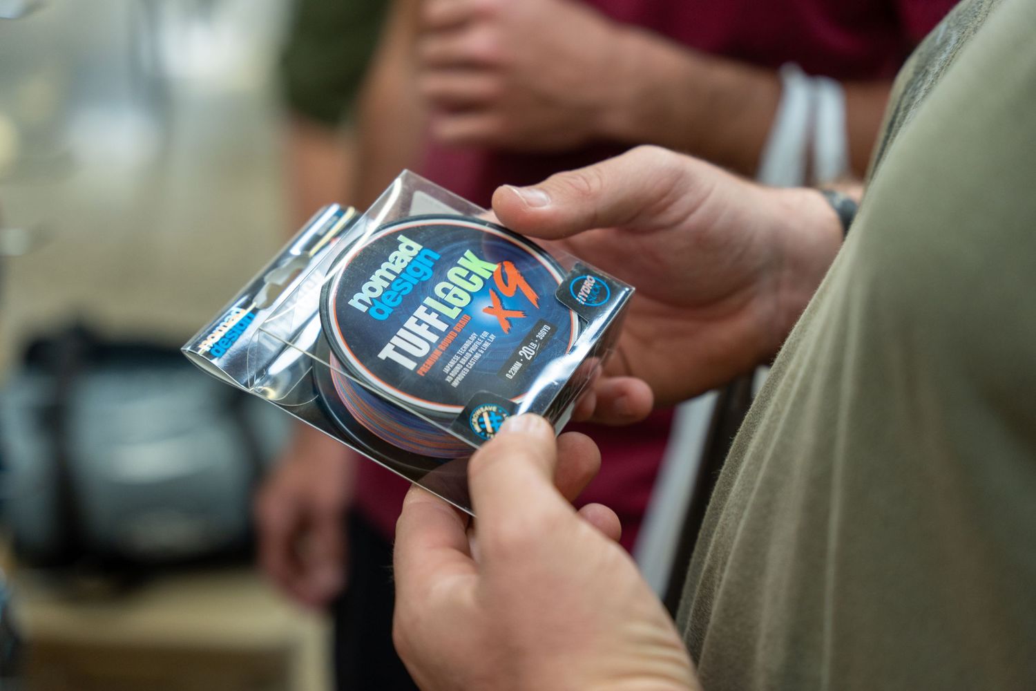 Hands holding and examining product packages at a retail display.