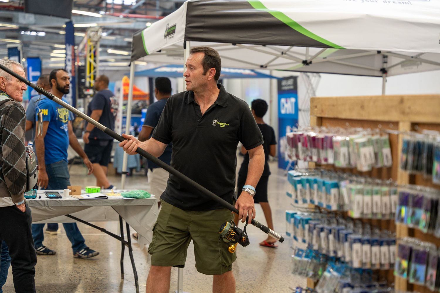 Shopping area with merchandise displays and vendor booths under fluorescent lighting.