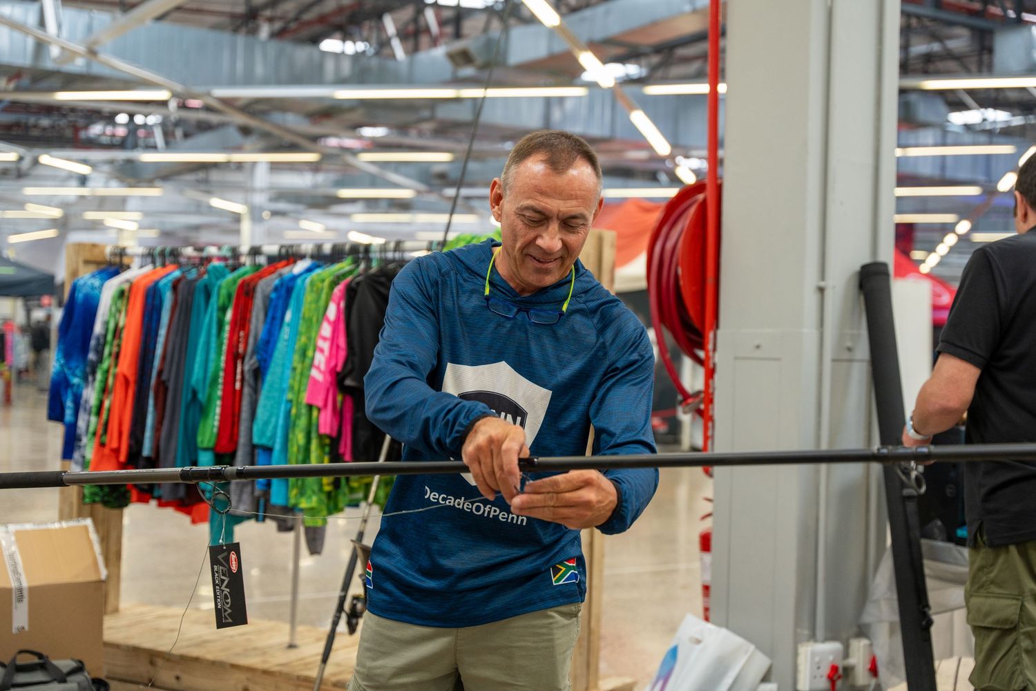 People using mobile devices while standing in a retail environment with clothing displays.