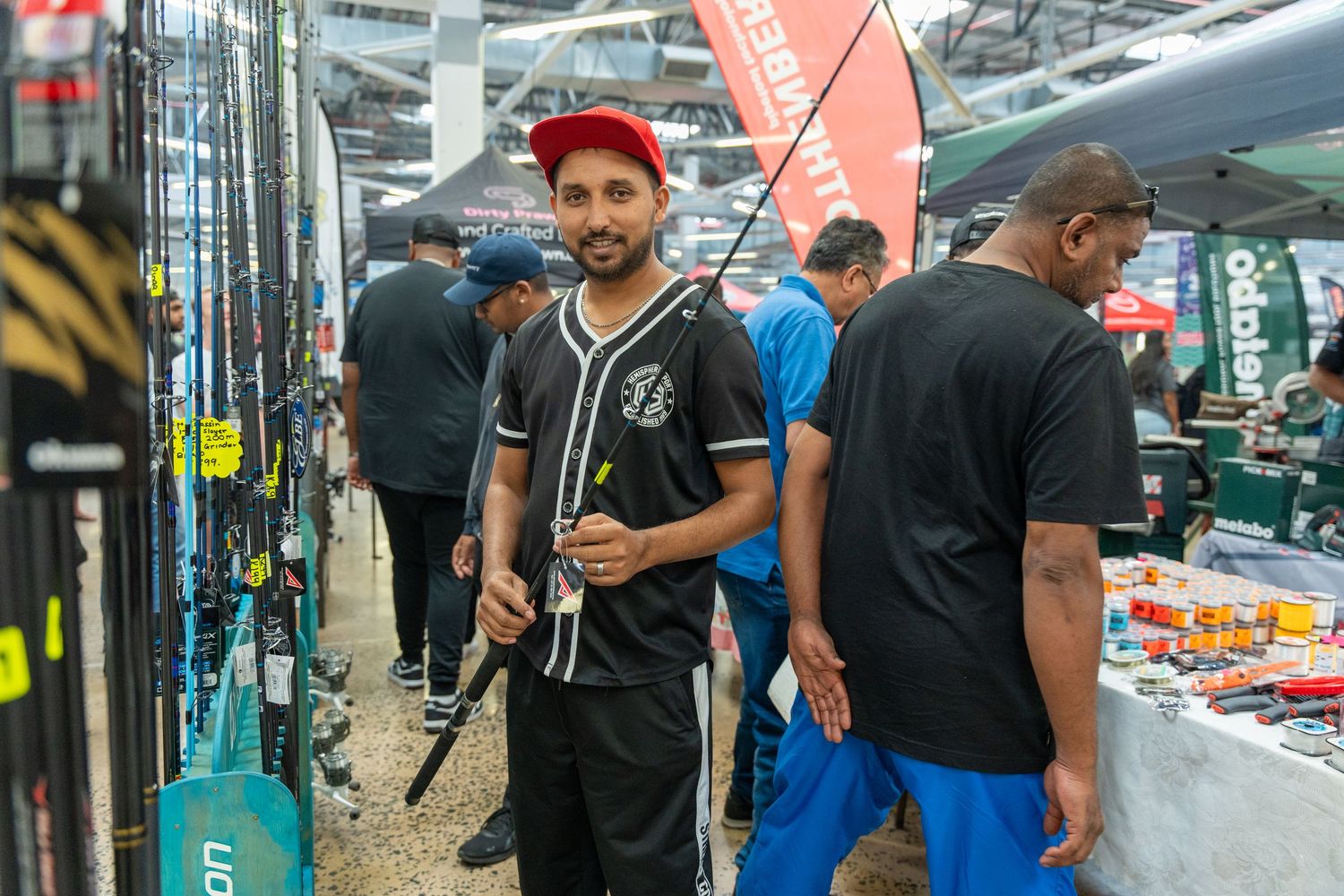 Competitors gathered at an indoor tournament venue with display banners and gaming equipment.