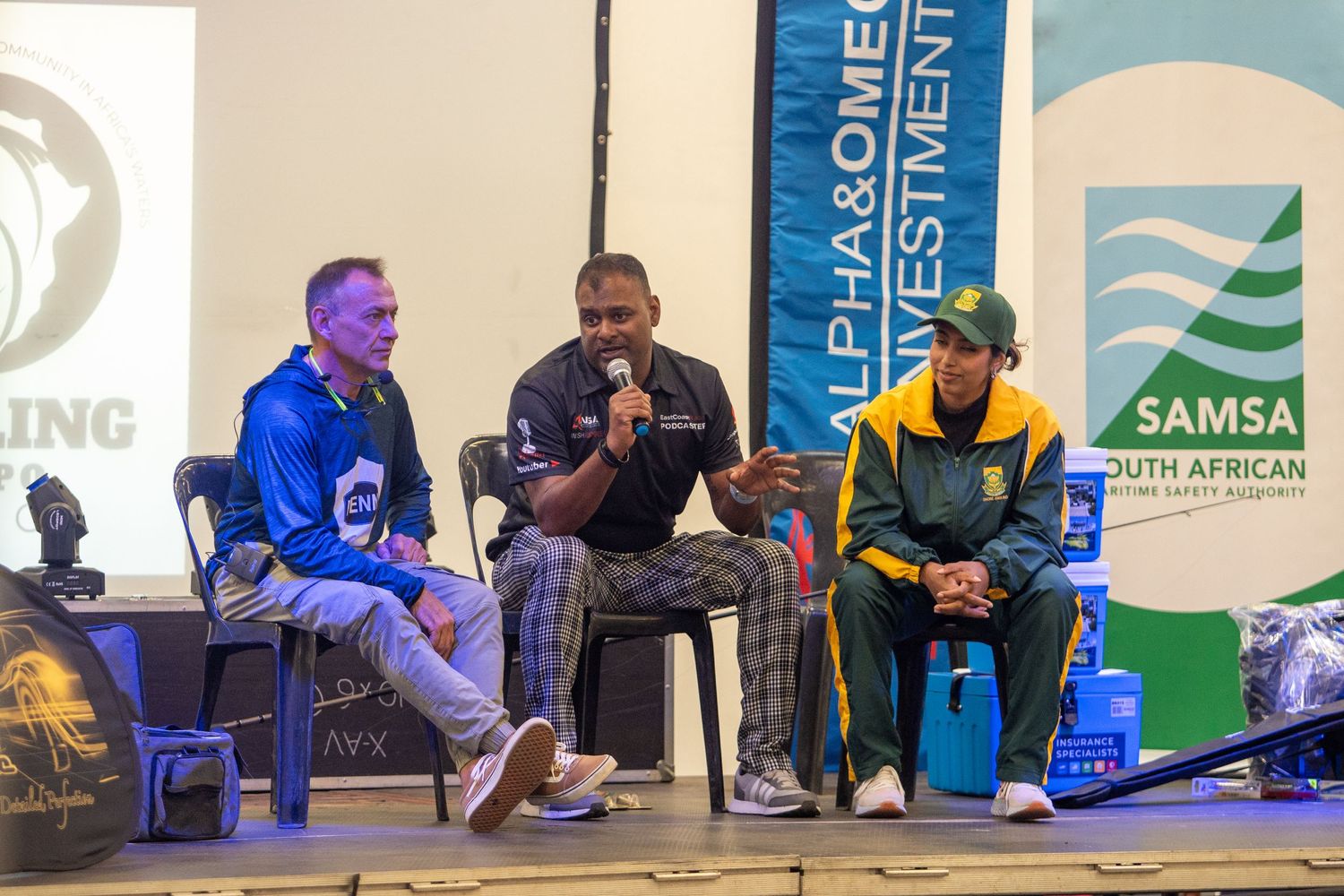 Contestants seated in a row at a competitive gaming event with promotional banners.
