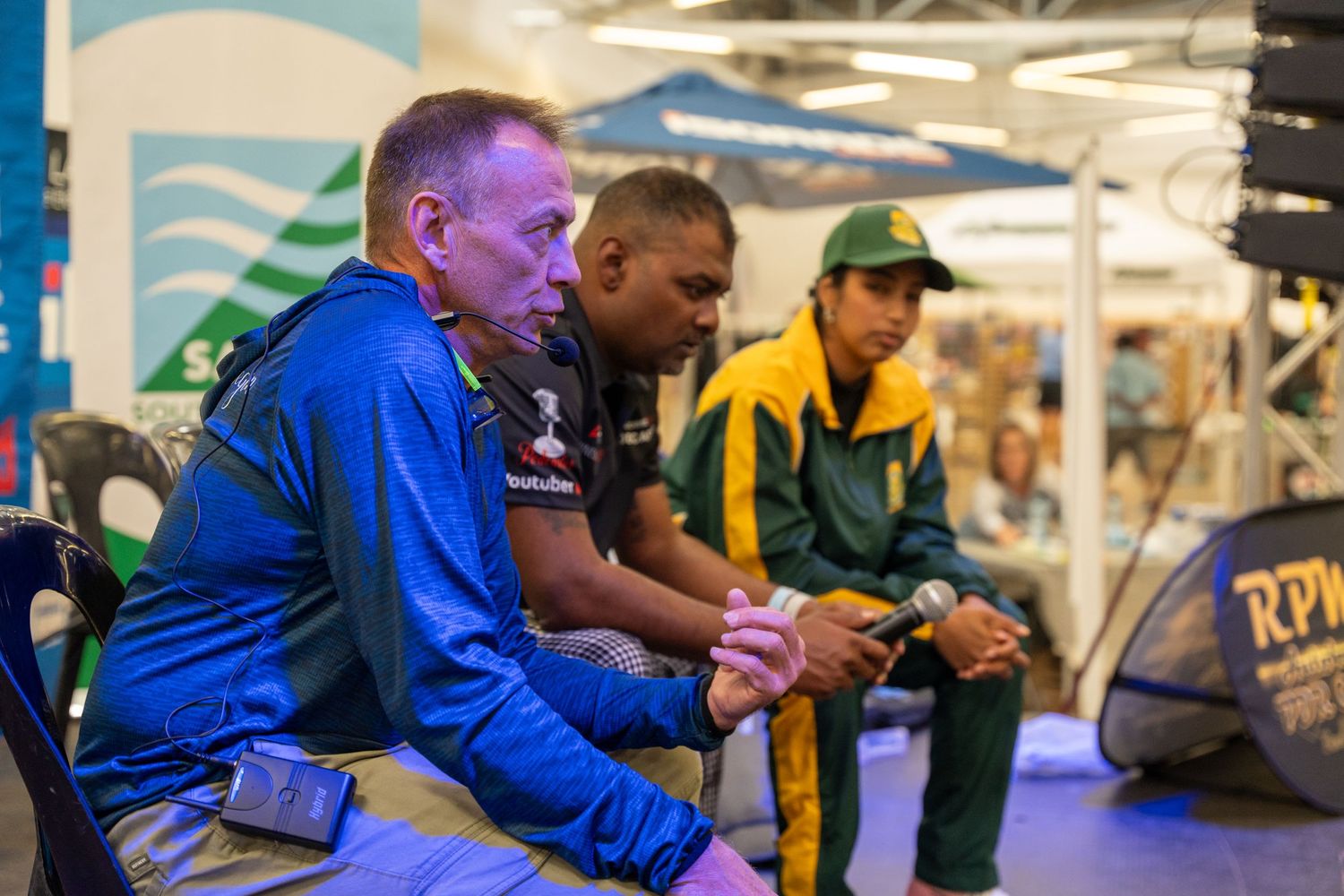 People competing in an indoor tournament with blue banners and promotional displays.