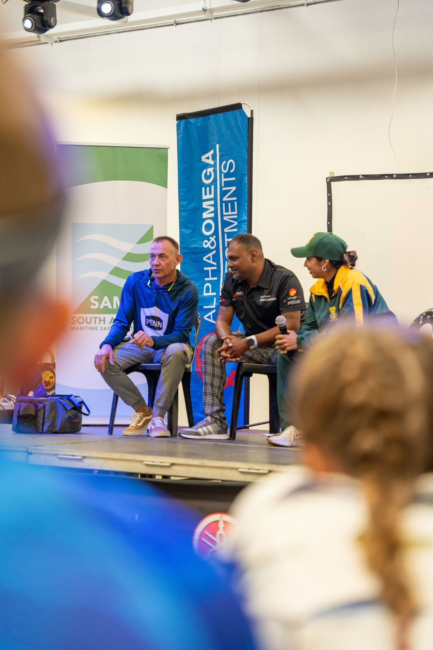 Participants seated in chairs during competitive event with branded banners and lighting.