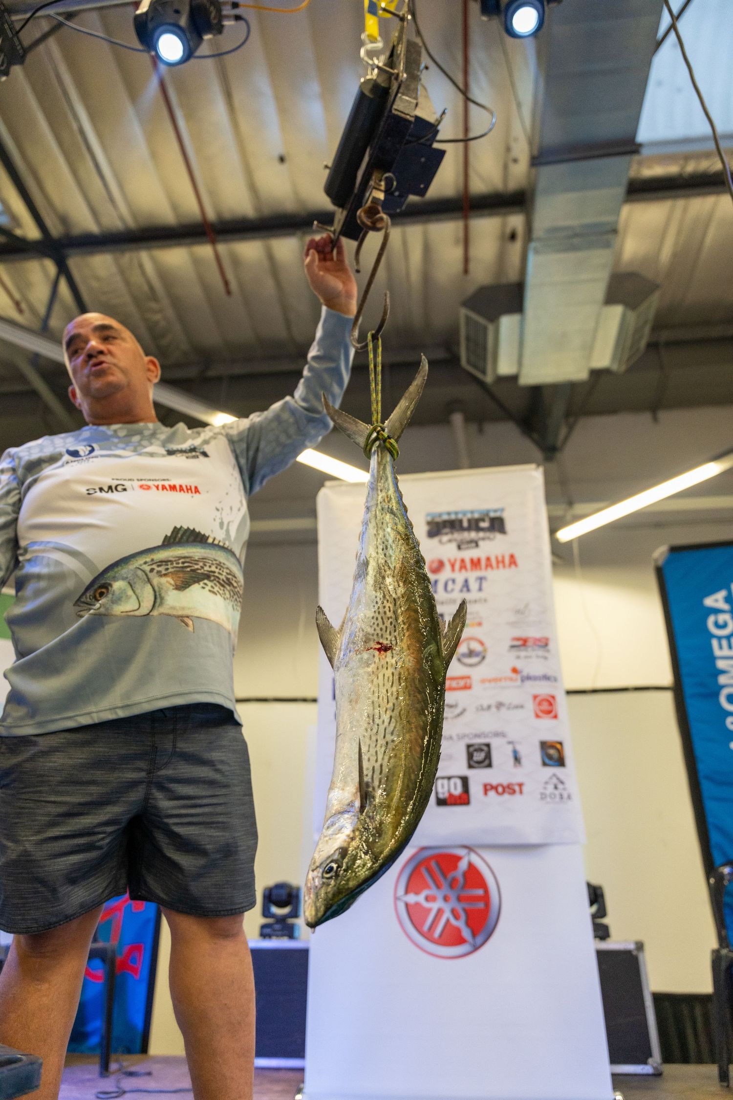 Competitors displaying caught fish at an indoor fishing tournament.
