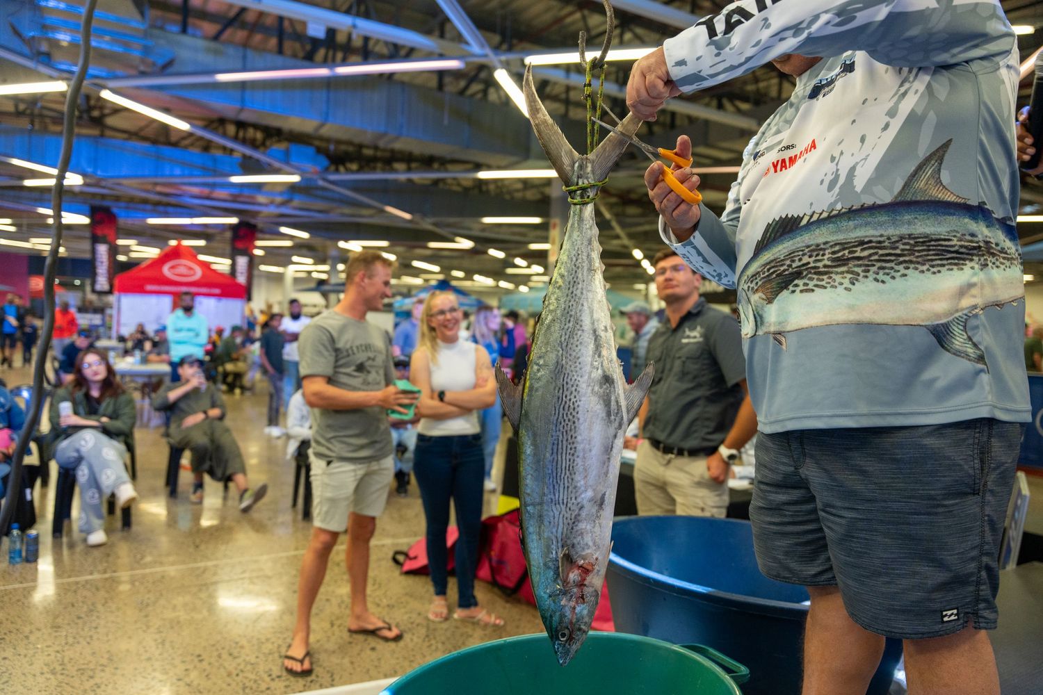 Busy fish market scene with large tuna displayed and people browsing stalls.