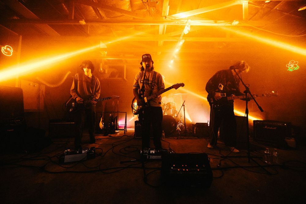 Musicians perform on stage bathed in intense orange lighting creating a dramatic atmosphere.