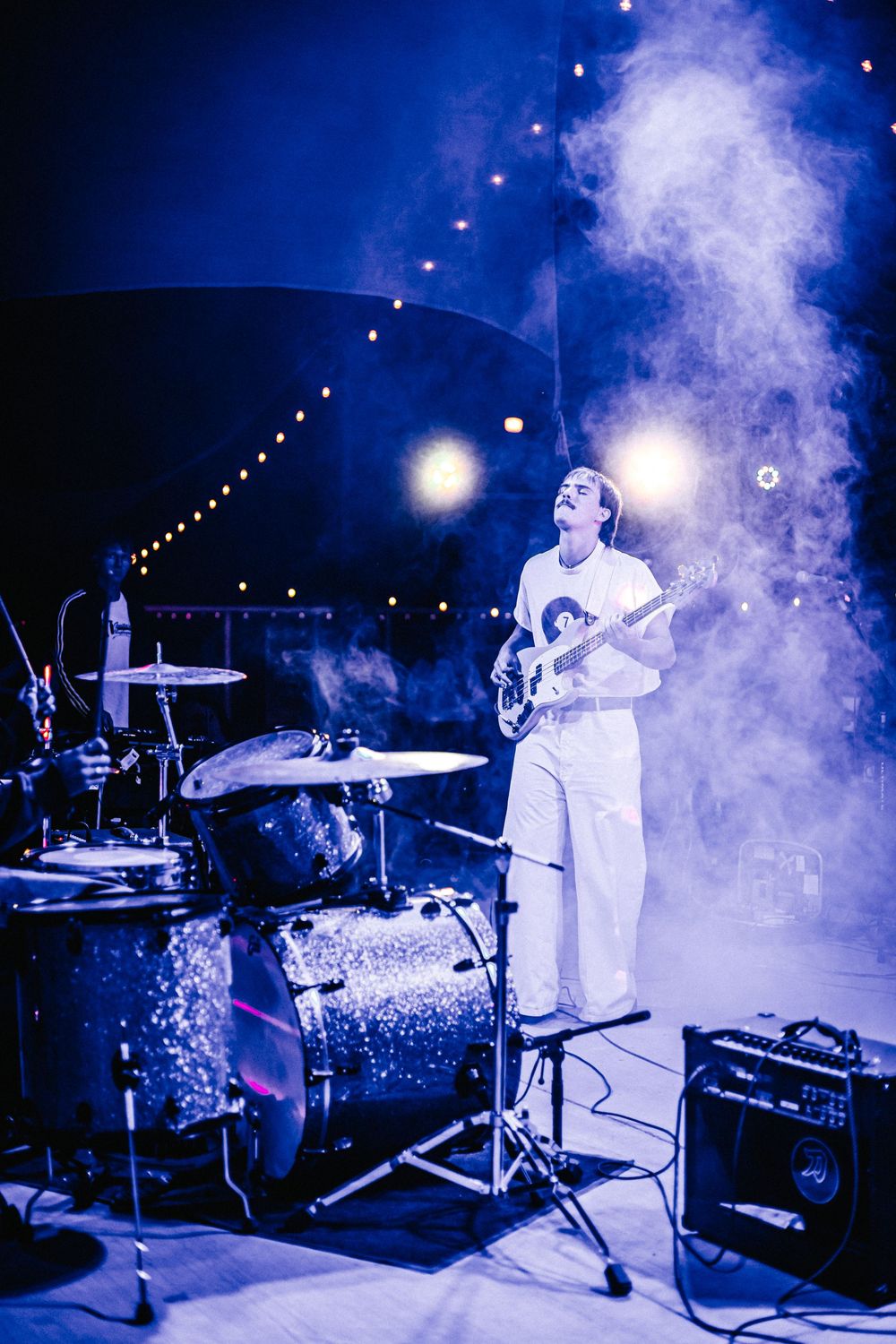 Musicians perform on stage with atmospheric blue lighting and fog effects during a live concert performance.
