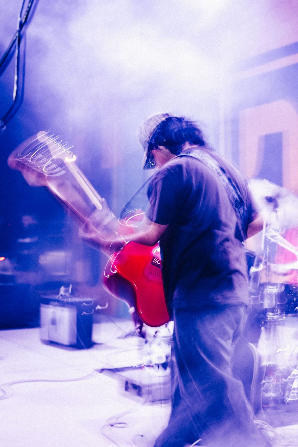 Musicians performing on stage with dramatic blue and purple lighting effects creating a dynamic concert atmosphere.